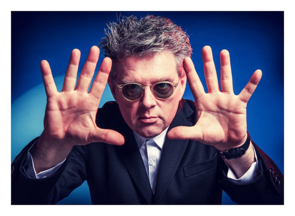 Tom Bailey holding up hands with blue background