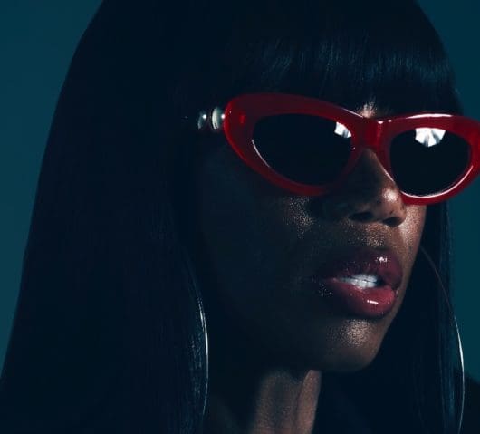 Shaznay Lewis pictured wearing red shades with glitter on her face