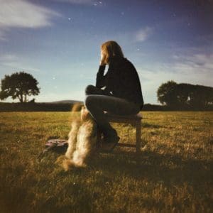 Beth Gibbons seated in a field